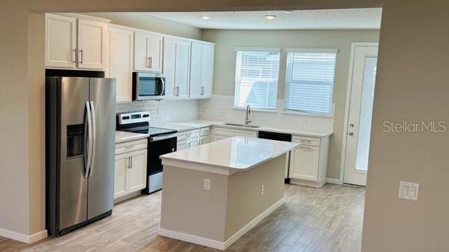 kitchen featuring a kitchen island, light hardwood / wood-style flooring, sink, stainless steel appliances, and white cabinets