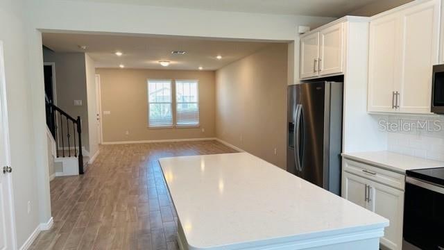 kitchen with light wood-type flooring, white cabinets, appliances with stainless steel finishes, and a center island