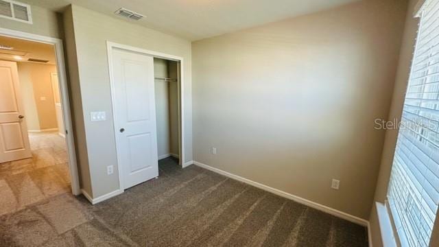 unfurnished bedroom with a closet and dark colored carpet