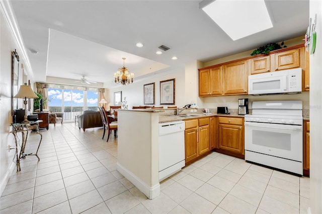 kitchen featuring ceiling fan with notable chandelier, white appliances, a skylight, kitchen peninsula, and sink