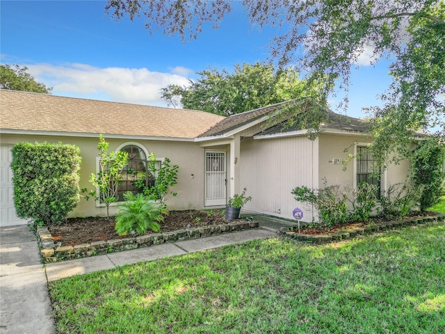 ranch-style home featuring a front lawn, an attached garage, and a shingled roof