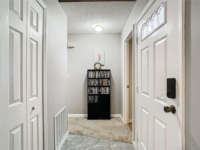 interior space featuring a textured ceiling and light colored carpet