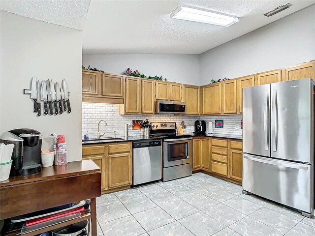 kitchen featuring a textured ceiling, stainless steel appliances, sink, decorative backsplash, and lofted ceiling