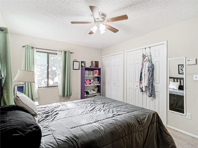 carpeted bedroom with two closets, ceiling fan, and a textured ceiling