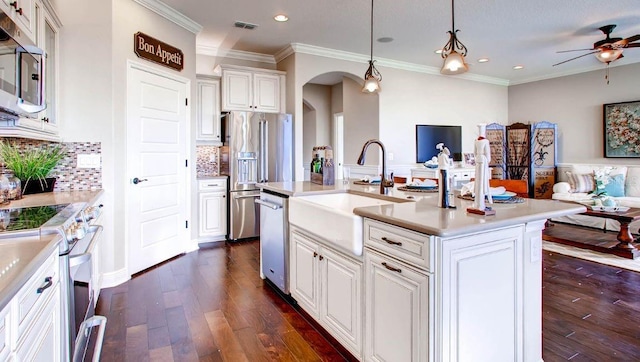 kitchen featuring ornamental molding, ceiling fan, decorative backsplash, dark wood-type flooring, and appliances with stainless steel finishes