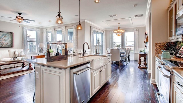 kitchen featuring decorative light fixtures, dark hardwood / wood-style flooring, a center island with sink, and a healthy amount of sunlight