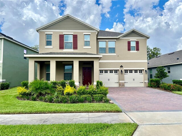 traditional-style house with a garage, decorative driveway, and stucco siding