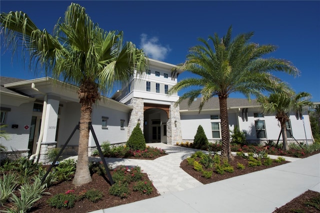 view of front of home featuring driveway, stone siding, and stucco siding