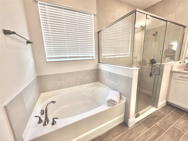 bathroom with a stall shower, vanity, and a bath