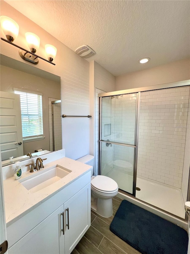 full bath with visible vents, toilet, wood tiled floor, vanity, and a shower stall