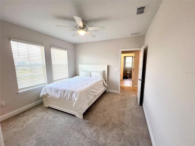 carpeted bedroom with a textured ceiling, a ceiling fan, visible vents, and baseboards