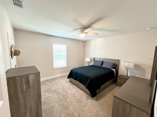 bedroom with light colored carpet, visible vents, a ceiling fan, a textured ceiling, and baseboards