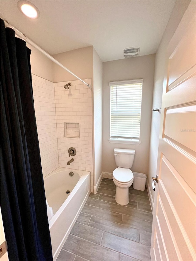 full bath featuring baseboards, visible vents, toilet, wood finish floors, and shower / washtub combination