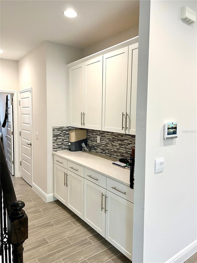 kitchen with tasteful backsplash, baseboards, white cabinets, wood tiled floor, and light countertops