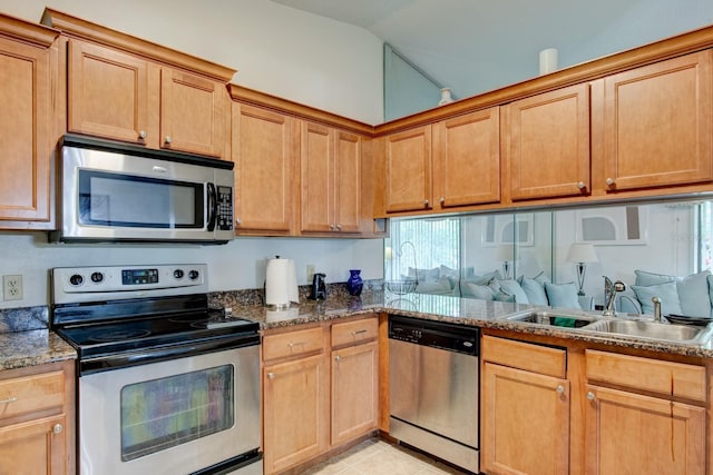 kitchen featuring vaulted ceiling, appliances with stainless steel finishes, sink, dark stone countertops, and light tile patterned floors