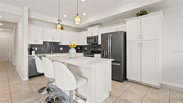 kitchen featuring appliances with stainless steel finishes, white cabinetry, a center island, and light tile patterned flooring