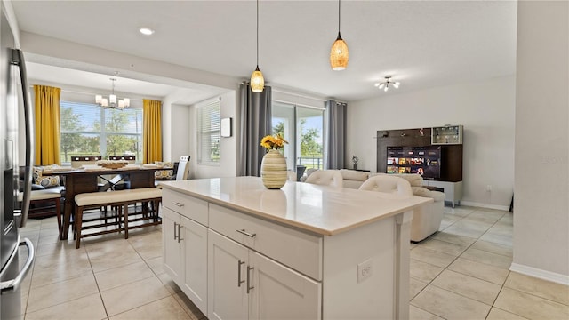 kitchen with a wealth of natural light, a center island, white cabinets, and hanging light fixtures