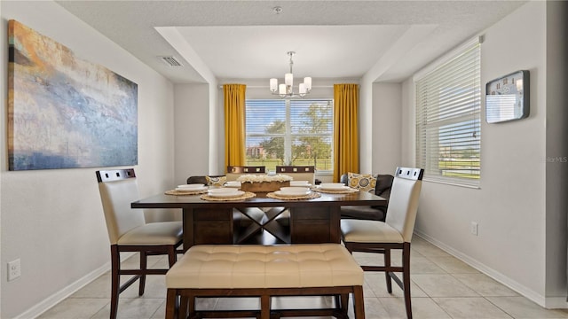 dining space with light tile patterned floors, a notable chandelier, and a textured ceiling