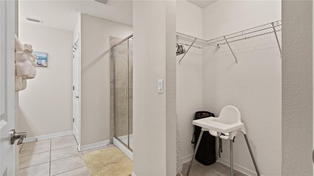 bathroom with tile patterned floors, a textured ceiling, and a shower with shower door