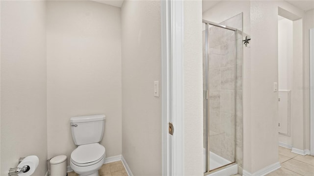 bathroom featuring toilet, a shower with shower door, and tile patterned floors