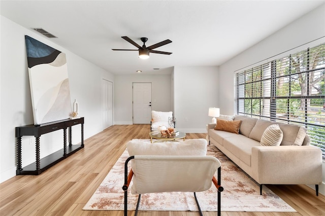 living room with light hardwood / wood-style floors, ceiling fan, and a healthy amount of sunlight