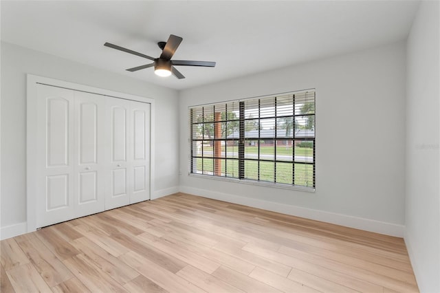 unfurnished bedroom featuring light wood-type flooring, ceiling fan, and a closet