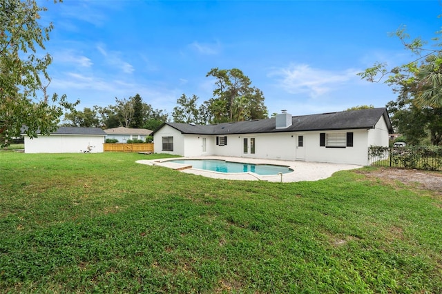 rear view of property with a fenced in pool, a patio area, and a lawn