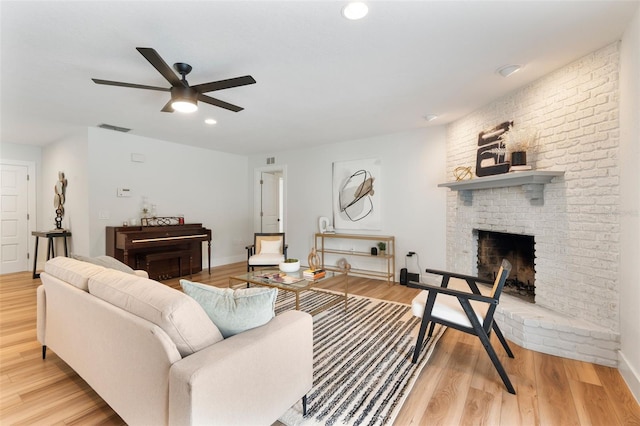 living room with a fireplace, light hardwood / wood-style floors, and ceiling fan