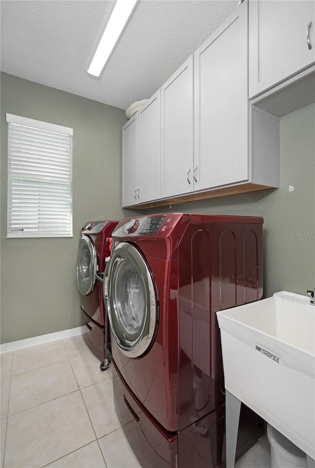 clothes washing area with separate washer and dryer, light tile patterned floors, sink, and cabinets