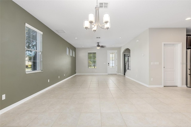 tiled empty room with ceiling fan with notable chandelier and a wealth of natural light