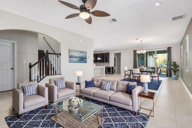 tiled living room featuring ceiling fan with notable chandelier