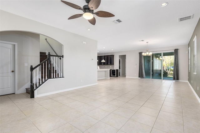 unfurnished living room with light tile patterned floors and ceiling fan with notable chandelier