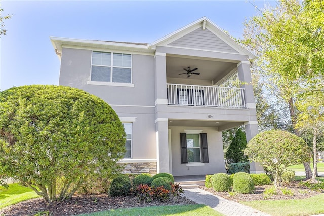 view of front of home with ceiling fan and a balcony