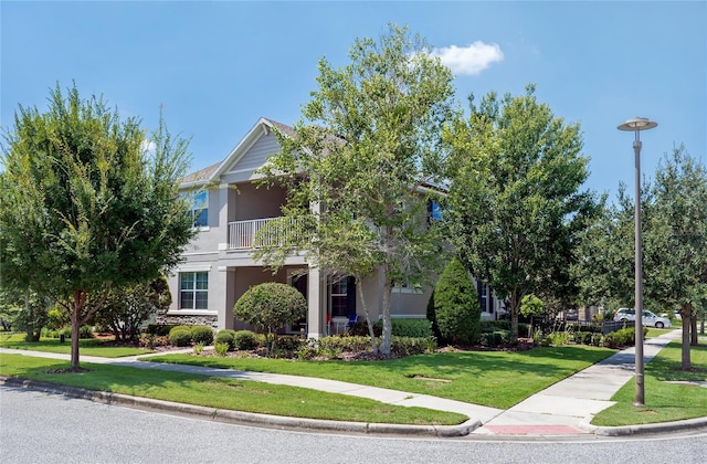 view of front of home featuring a balcony and a front yard