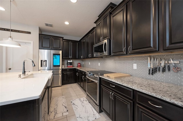 kitchen with pendant lighting, sink, stainless steel appliances, tasteful backsplash, and light tile patterned flooring