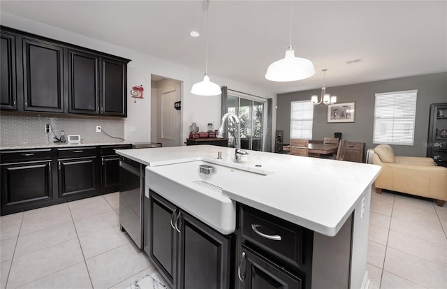 kitchen with black dishwasher, tasteful backsplash, a center island with sink, decorative light fixtures, and a chandelier