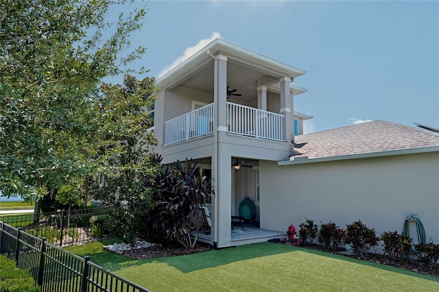 back of house with a balcony, a yard, and ceiling fan