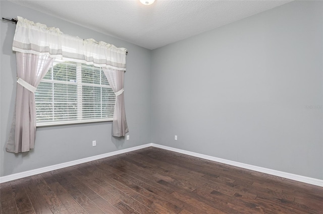 spare room featuring dark hardwood / wood-style floors and a textured ceiling