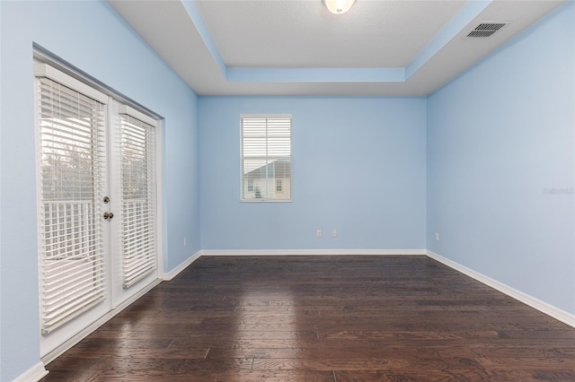 spare room with a raised ceiling and dark hardwood / wood-style floors