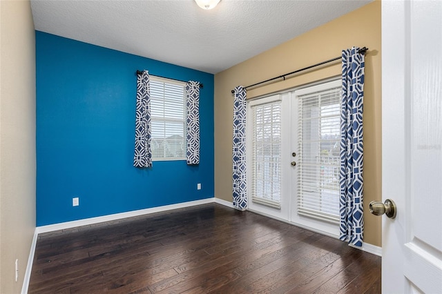 unfurnished room featuring dark hardwood / wood-style floors, a textured ceiling, and french doors