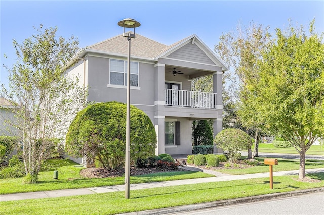 view of front of property featuring ceiling fan, a balcony, and a front yard