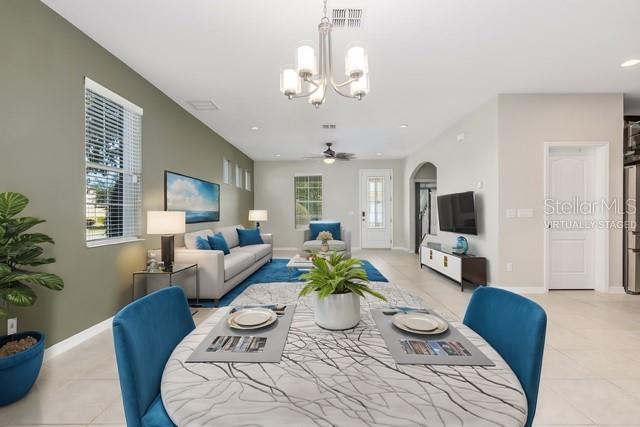 tiled living room featuring a healthy amount of sunlight and ceiling fan with notable chandelier