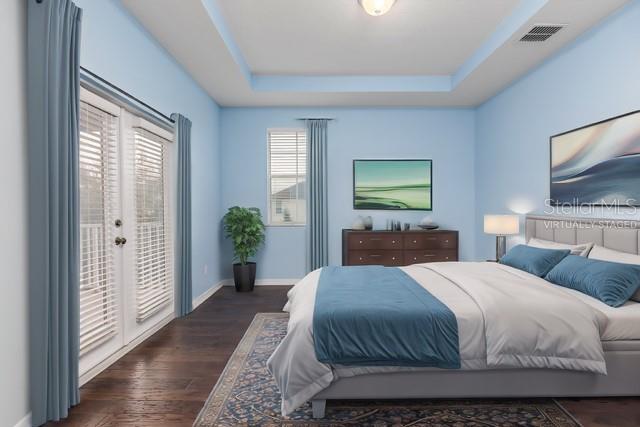 bedroom with dark hardwood / wood-style flooring, a raised ceiling, and access to outside