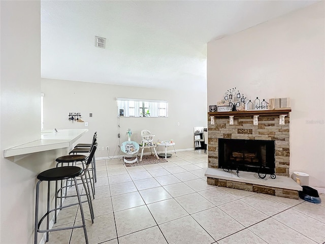 living room featuring light tile patterned floors and a stone fireplace