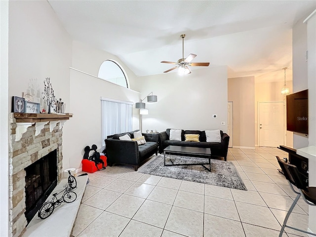 living room featuring lofted ceiling, light tile patterned floors, ceiling fan, and a stone fireplace