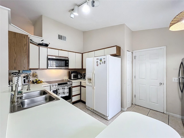 kitchen with sink, light tile patterned floors, appliances with stainless steel finishes, and white cabinetry