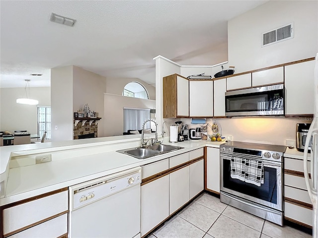 kitchen featuring white cabinets, appliances with stainless steel finishes, sink, light tile patterned flooring, and a stone fireplace