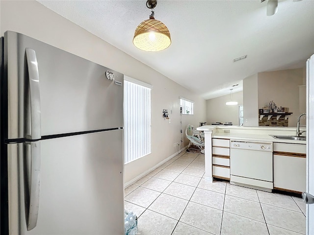 kitchen featuring vaulted ceiling, stainless steel fridge, dishwasher, pendant lighting, and sink