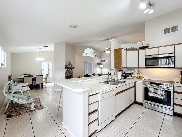 kitchen with appliances with stainless steel finishes, lofted ceiling, kitchen peninsula, and sink