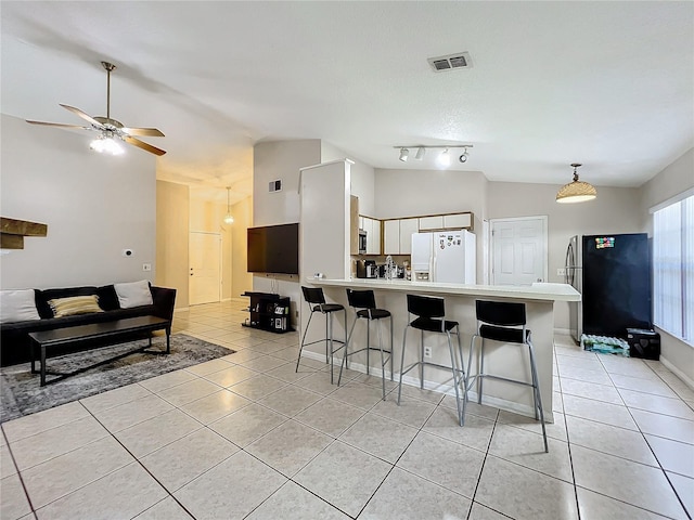 kitchen featuring vaulted ceiling, a breakfast bar area, stainless steel appliances, white cabinetry, and ceiling fan